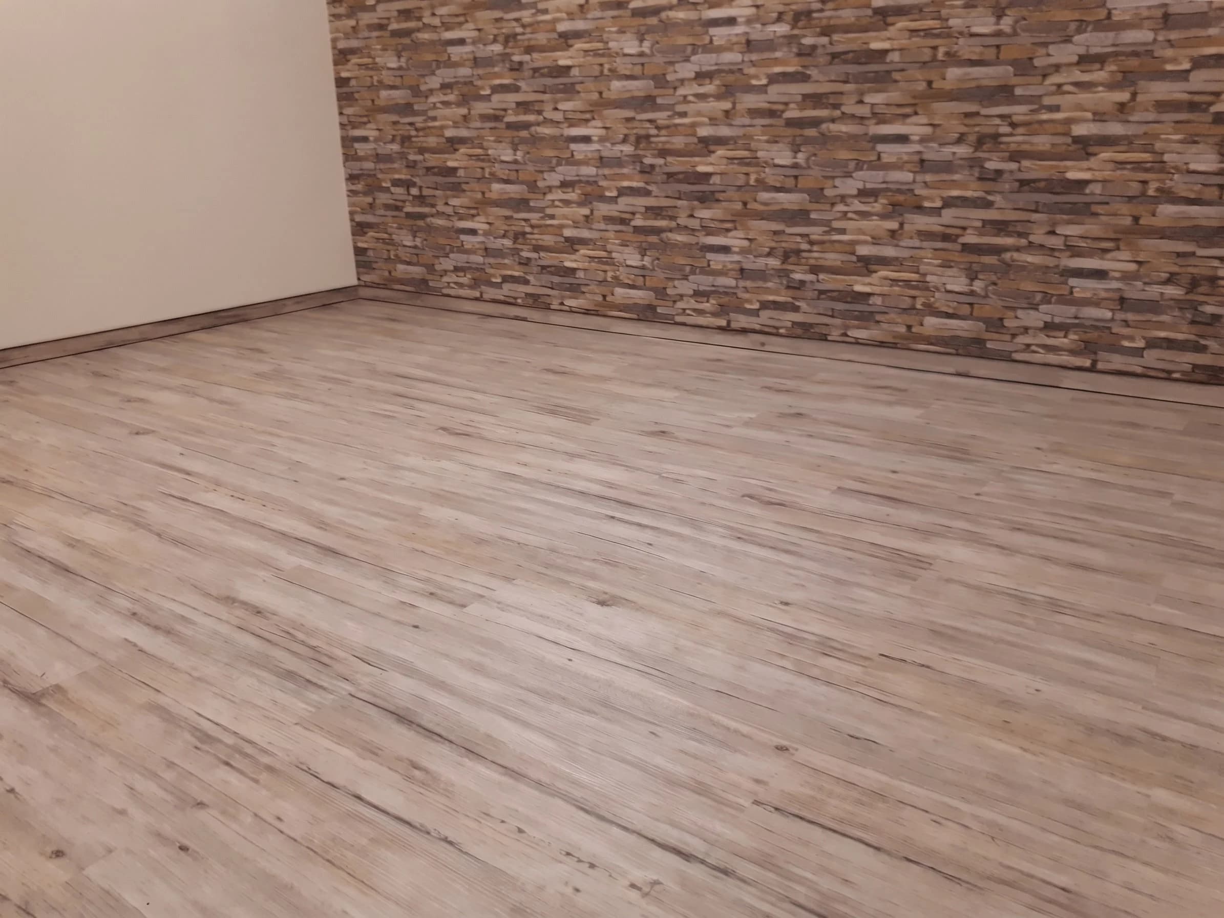Heller Vinylboden in Holzoptik vor einer Wand aus Steinriemchen