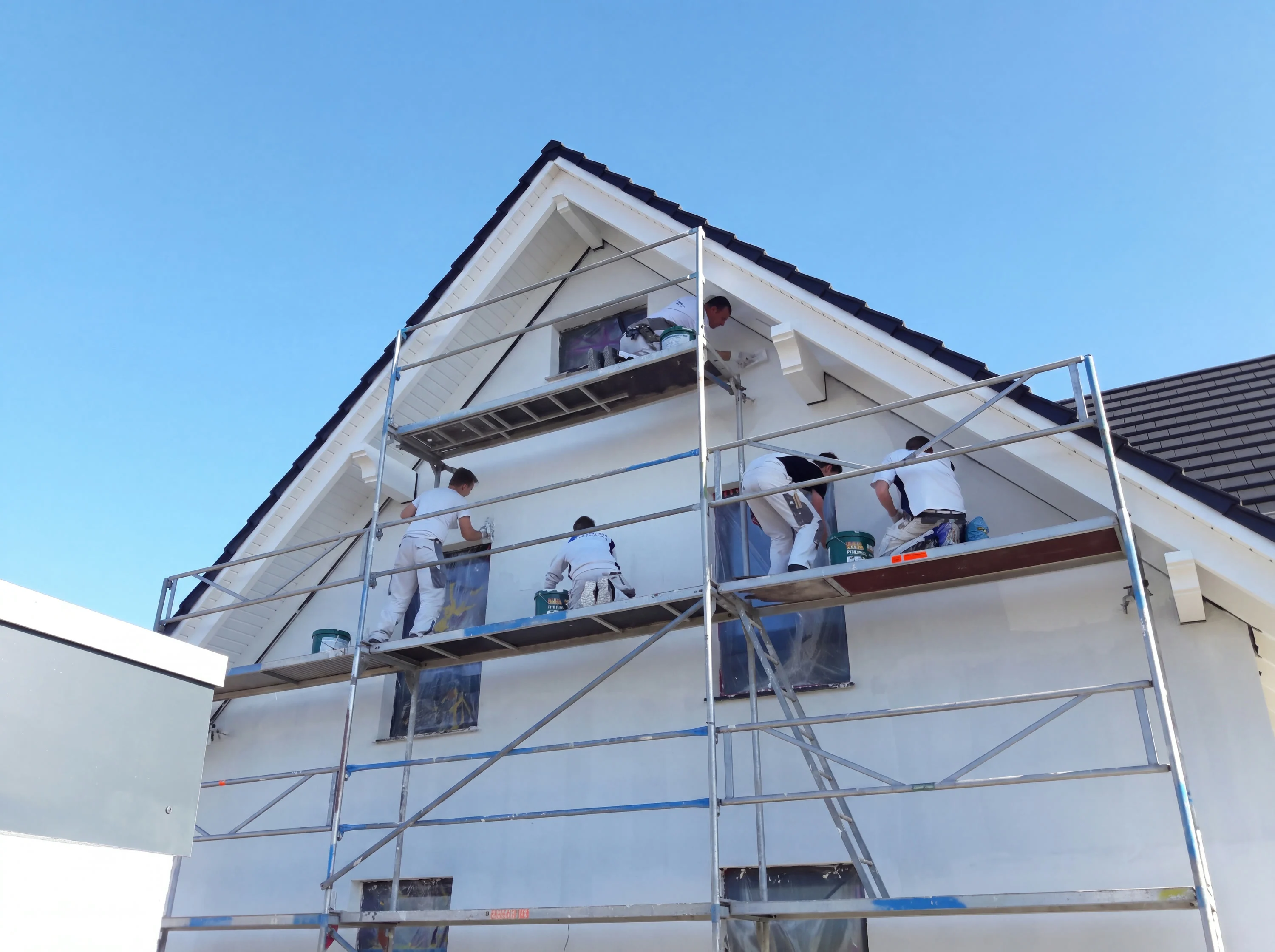 Fünf Mitarbeiter von A. Horn verputzen einen Hausgiebel vom Gerüst aus